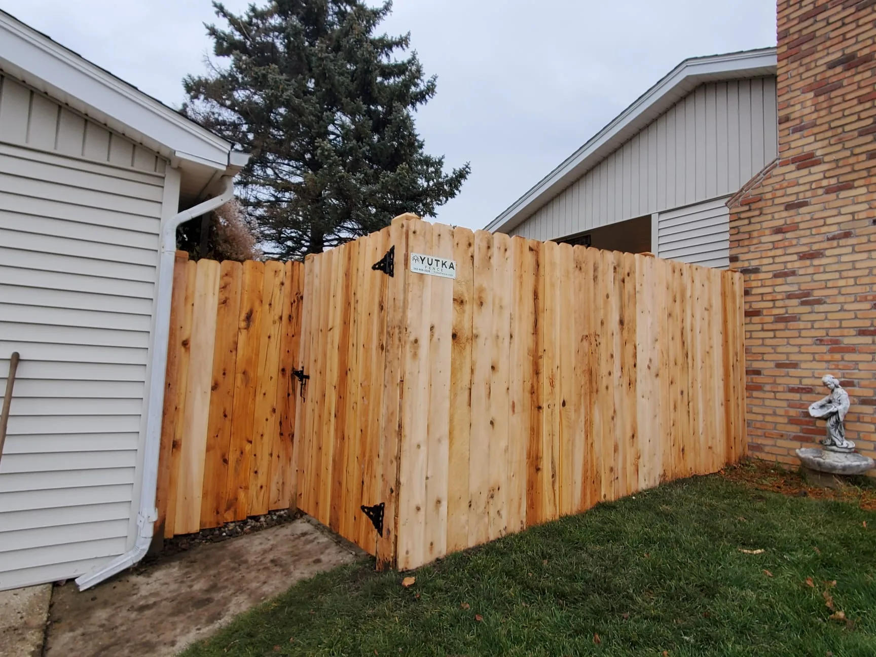 Newly installed cedar fence with Yutka Fence logo on corner